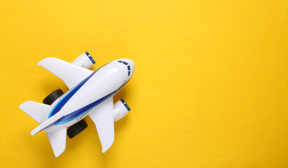 Toy passenger plane on yellow background. Travel concept. Copy space. Top view