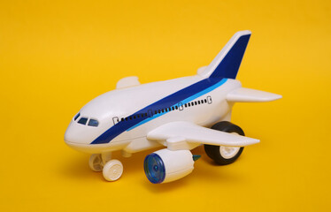 Fototapeta premium Toy passenger plane on yellow background. Travel concept.