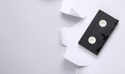 Retro video casette and white torn paper sheet on gray background. Top view