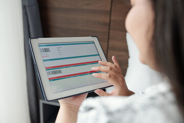 Close-up image of woman entering personal information when buying plane ticket via application on tablet computer