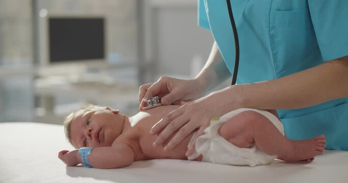Pediatric doctor exams newborn baby with stethoscope in hospital