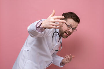 Cute doctor with a stethoscope around neck makes a greeting gesture with hands and looks at the camera smiling. Welcome to the clinic.