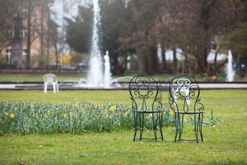 Vintage Stühle im Stadtpark mit Wasserfontäne und Blumen im Grünen