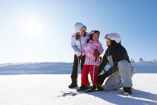 Young parents teaching daughter to ski