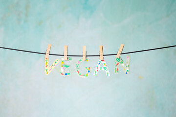 Word VEGAN in wooden letters painted with vegetables and hung with clothespins on a rope on a Green background. Health Concept