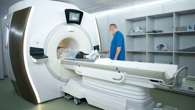 Magnetic resonance imaging in the modern hospital, adult man doctor performs a magnetic tomographic examination of a young dark-skinned woman, MRI, modern technologies in medicine.