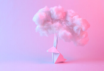 Origami bunny with fluffy cloud in pastel pink blue light. Creative easter idea. Minimal concept