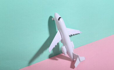Toy airplane on blue-pink background. Minimalism. Trendy shadow. Creative layout. Travel concept