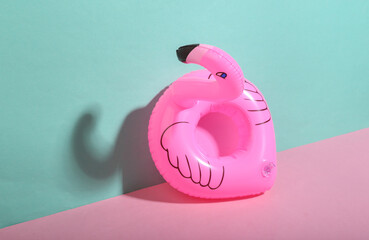 Inflatable flamingo on blue-pink background. Minimalism. Trendy shadow. Creative layout.