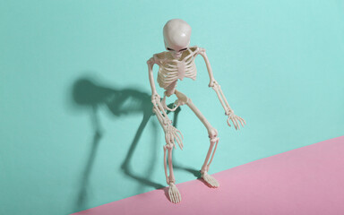 Creepy skeleton on blue-pink pastel background. Minimalism. Trendy shadow. Creative layout.