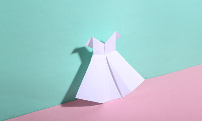 Origami white dress on blue-pink pastel background. Minimalism. Trendy shadow. Creative layout.