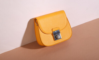 Creative modern fashion still life. Yellow bag on beige brown background. Minimalism. Trendy shadow.