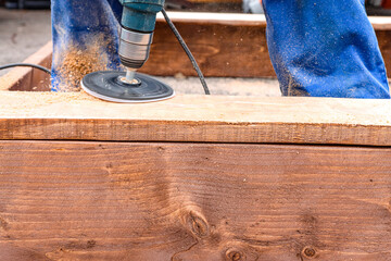 Sanding wood with professional equipment outdoors. A carpenter is working with a product. Sawdust...