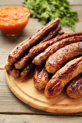 Grilled sausages on wooden board on grey background