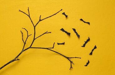 Creative Halloween layout. Tree branch and flying bats on yellow background. Flat lay
