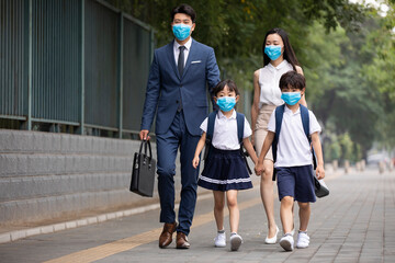 Young family wearing surgical masks and walking outdoors