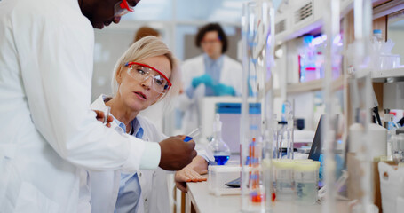 African male scientist consulting with mature colleague about samples in test tube