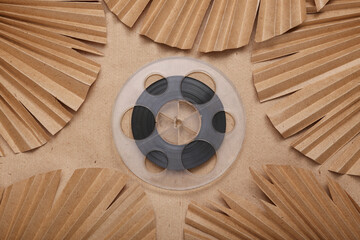 Creative layout. Film reel and palm leaves on beige background. Flat lay