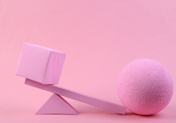 Balancing swing with cube and ball on pink background. Minimalism. Geometry shapes
