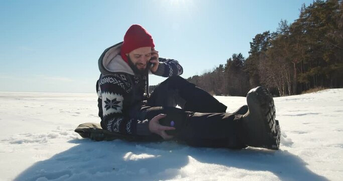 Mam with injured leg sitting on snow outdoors calling 911