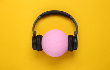 Fototapeta na wymiar Headphones with ball on yellow background. Minimalistic creative composition