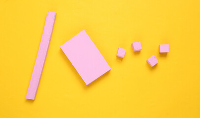 Layout composition of pink geometric shapes on yellow background. Flat lay