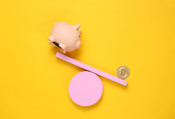 Balancing swing with piggy bank and bitcoin on yellow background. Minimalism. Geometry shapes. Creative layout