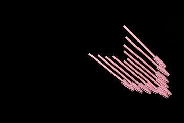 Pink eyelash brushes on a black background. Cosmetic accessories for eyelash extensions
