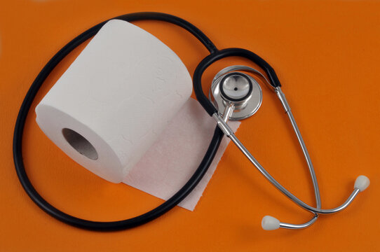 Concept de constipation avec un rouleau de papier toilette et un st&eacute;thoscope sur fond orange