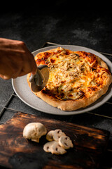 pizza con pollo y champiñones siendo cortada 