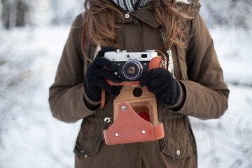 Woman photographer with retro camera in snowy weather at winter