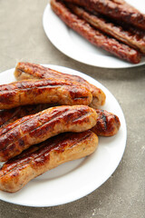 Grilled sausages on plate on grey background