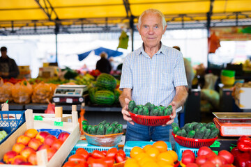 retired european man selling tomatoes in market