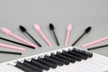 A tablet with false eyelashes and brushes on a black background. Cosmetic accessories for eyelash extensions
