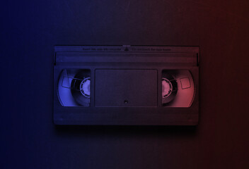 Video cassette in neon light. Retro storage media, videotape. 80s