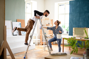 Mid adults couple having fun when painting indoors at home, relocation and diy concept. © Halfpoint