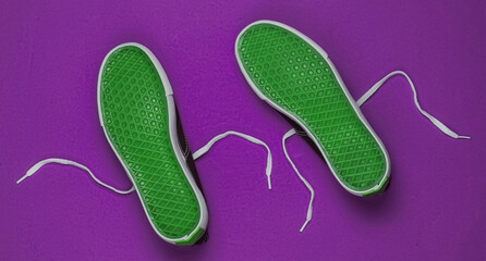 Sole up sneakers on purple background. Top view