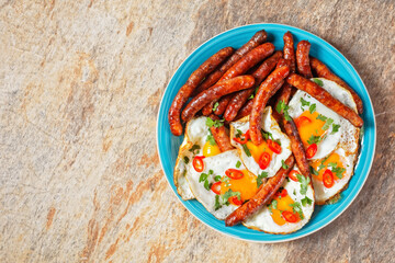 sausages with fried eggs on a plate, top view