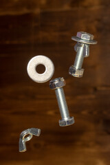 falling screws, washer and retaining nut on blurred brown background - 427245517