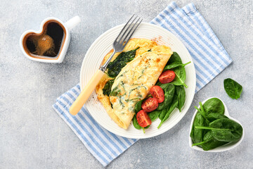 Omelet or omelette with spinach, cherry tomato and pepper seasoning on a white plate, on light grey background. Healthy breakfast concept. Top view.