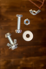 falling screws, washer and retaining nut on blurred brown background - 427245700