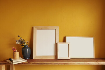 Wooden frames mockup. Composition with a flowerpot, dried artichokes, a notebook and a cup. Against the background of a yellow wall