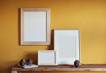 Wooden frames mockup. Composition with a dried artichokes, and book . Against the background of a yellow wall