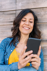 vertical view of woman connecting with technology with friends and family. Video call with mobile phone outdoors. Lifestyle with people and technology.