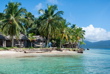 Palm trees on a tropical beach with crystal clear water to relax and cabanas to rest
