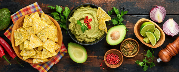 Guacamole. Traditional latinamerican Mexican dip sauce in a black bowl with avocado and ingredients...
