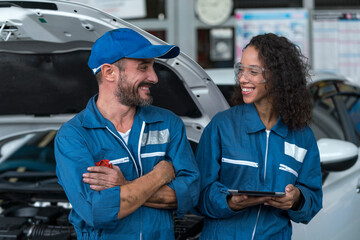 Auto services and Small business concepts. Auto mechanic hands using wrench to repair a car engine. Two happy auto mechanics in uniforms working in auto service.