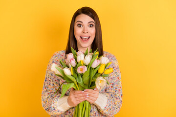 Photo of charming happy nice amazed woman hold flowers tulips surprise isolated on bright yellow color background