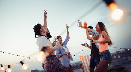 Having a great time with friends, having fun at rooftop party - obrazy, fototapety, plakaty