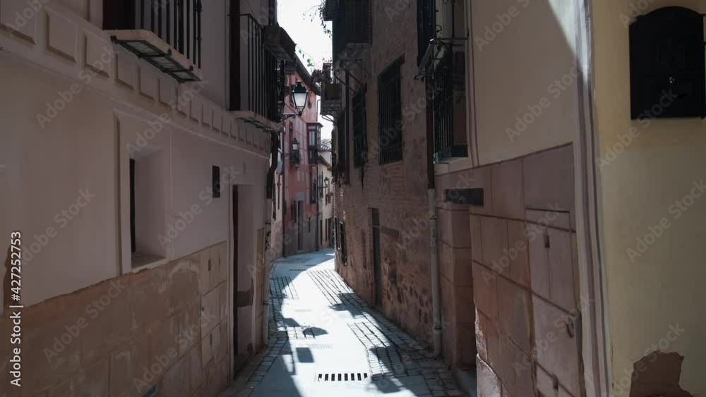 Sticker charming narrow street of old town of toledo city at sunny warm day. empty pedestrian cobblestone wa